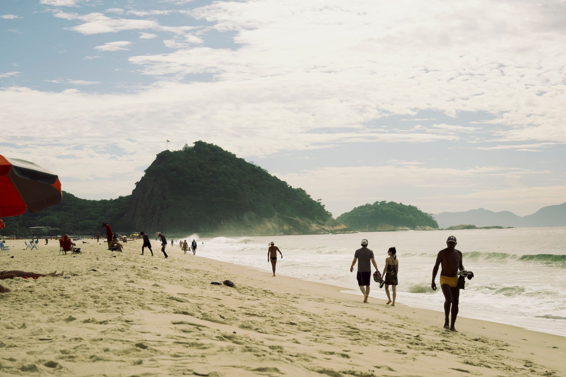 People enjoying the sun and sea at a picturesque beach in Rio de Janeiro, Brazil.